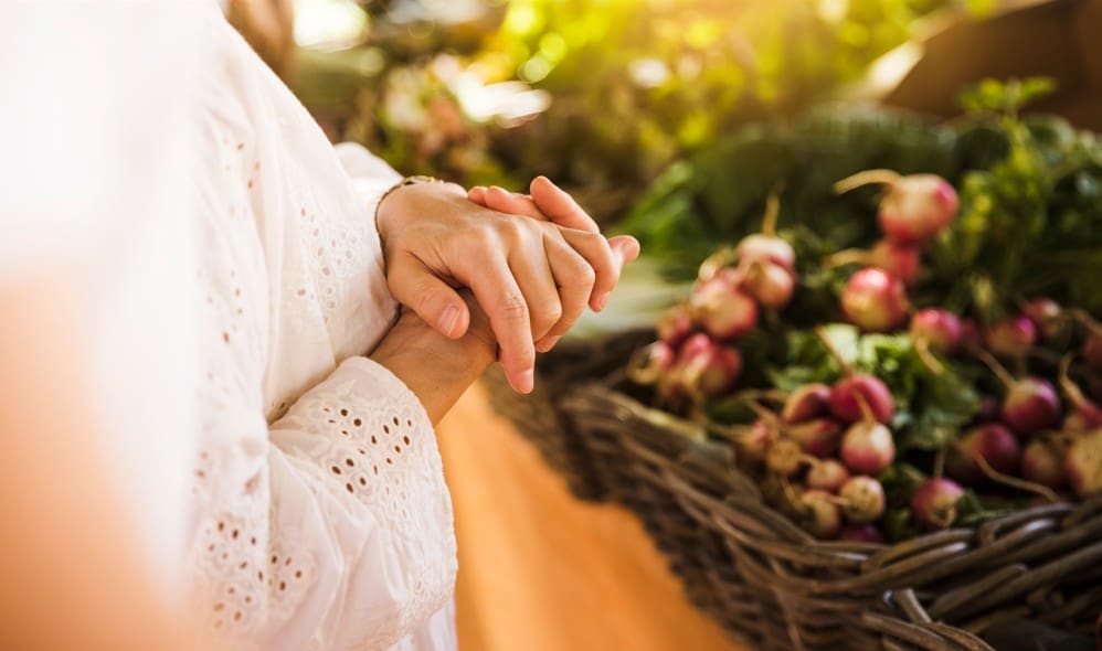 Manos de una mujer frente a una cesta de frutas