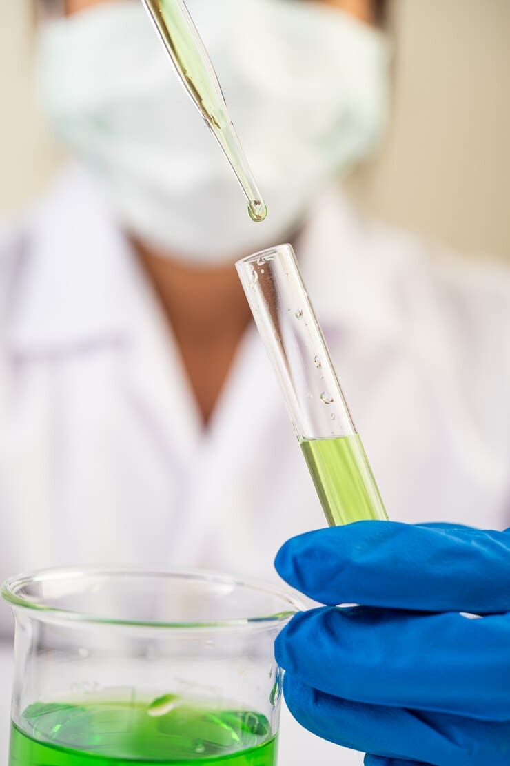 Cientifico con guantes en la mano agarrando un tubo de ensayo haciendo pruebas de laboratorio